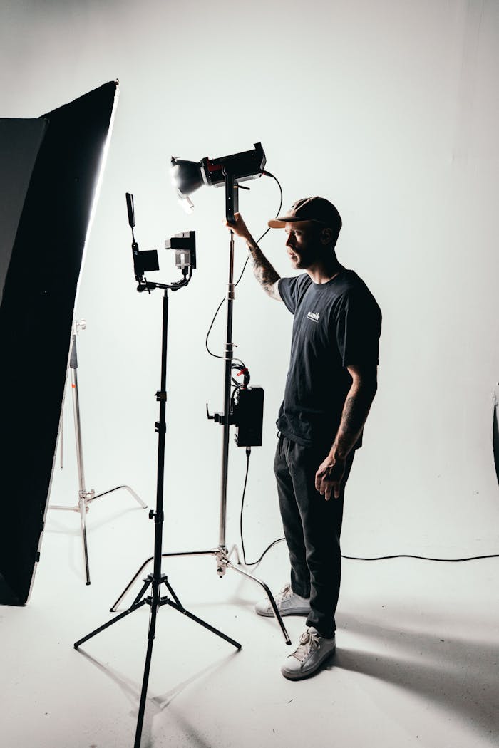 Photographer adjusting studio lights on set with professional equipment.