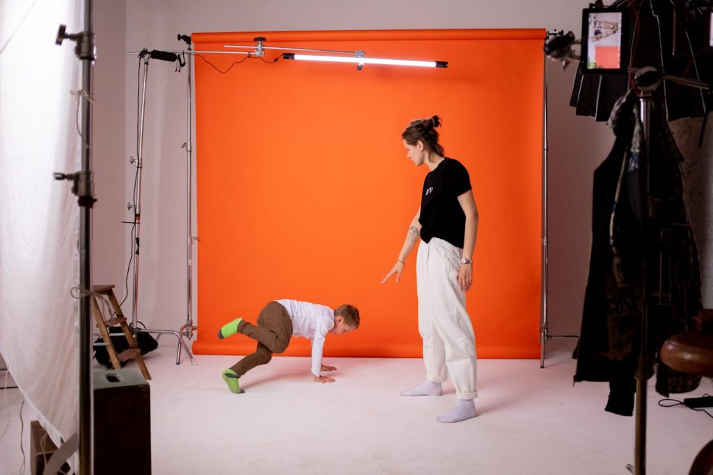 Capture of a young boy practicing dance moves with guidance in a photography studio.